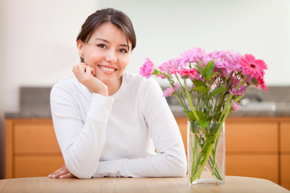 Beautiful woman next to a bunch of  flowers and smiling - indoors